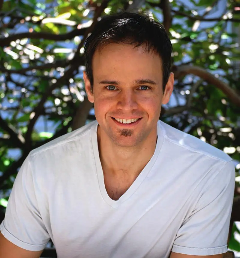 Smiling man in white shirt outdoors.